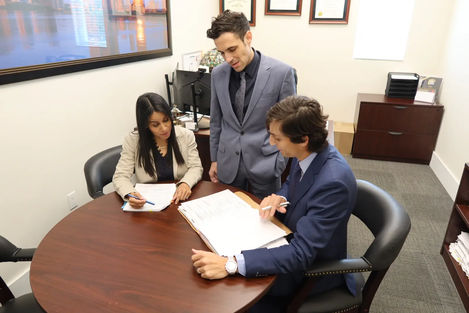 Los abogados Miriam Marenco, Stephen Cordero y Sean Cordero revisando el expediente de un cliente en la oficina del bufete en Miami