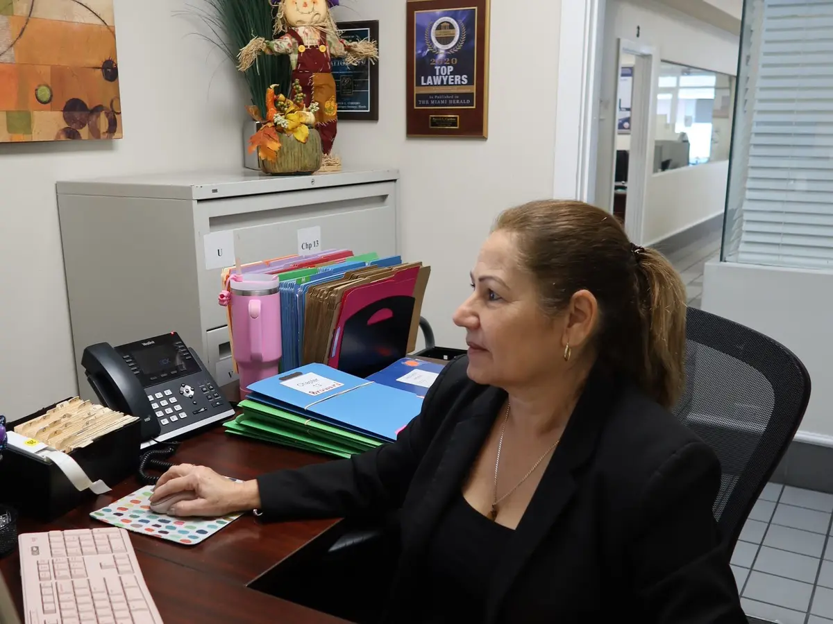 Una integrante del personal revisando expedientes en su escritorio en la oficina del bufete en Miami