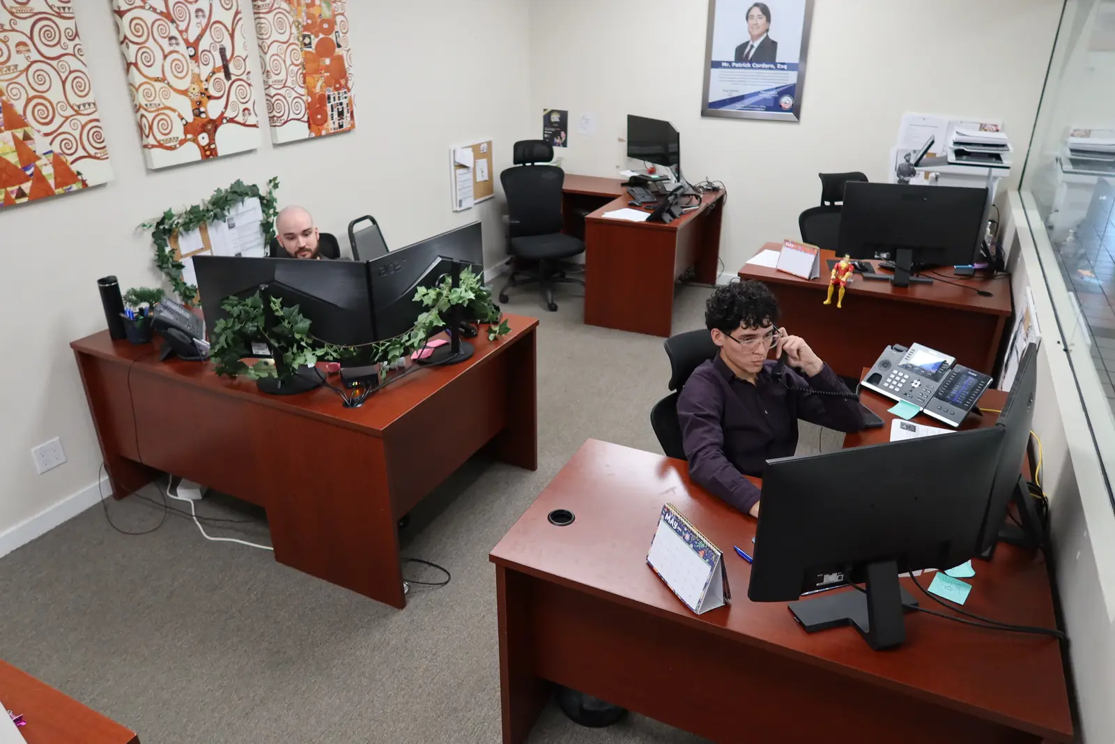 Dos integrantes del personal trabajando en sus escritorios en la oficina del bufete en Miami